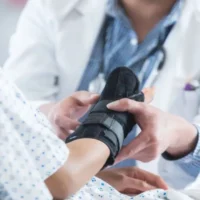 A Male Doctor Places an Arm Brace on a Patient's Sprained Wrist